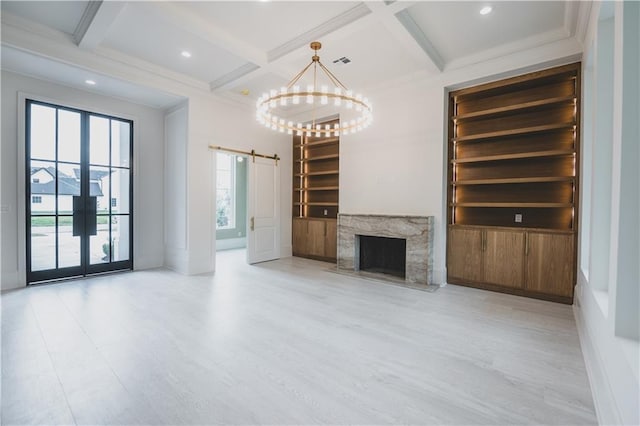 unfurnished living room featuring coffered ceiling, a barn door, built in shelves, and beamed ceiling