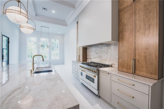 kitchen with sink, light stone counters, hanging light fixtures, range with two ovens, and white cabinets