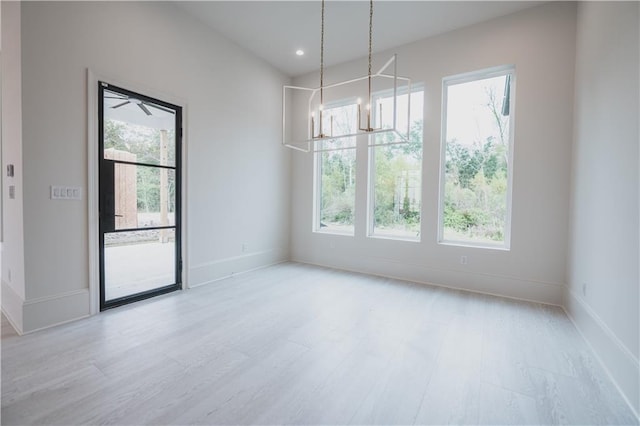 unfurnished dining area with a notable chandelier and light hardwood / wood-style floors