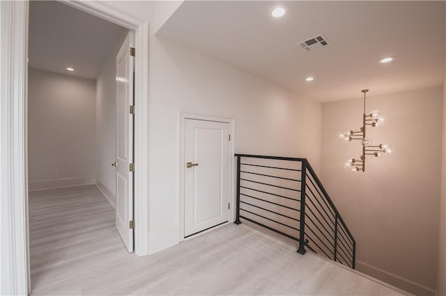 staircase with hardwood / wood-style flooring and a chandelier