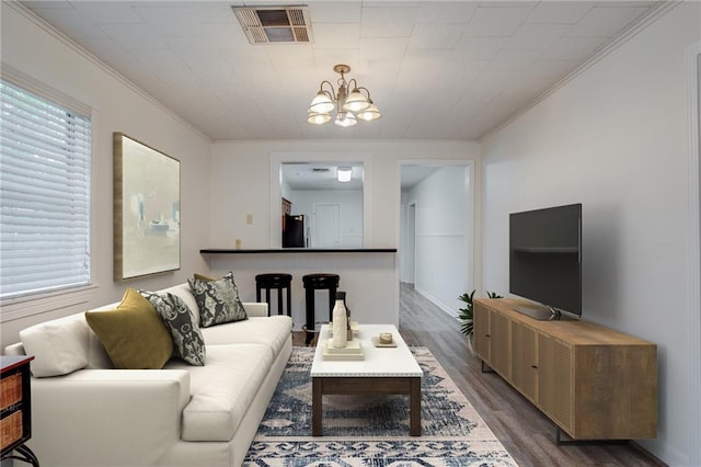 living room featuring crown molding, dark wood-type flooring, and a notable chandelier