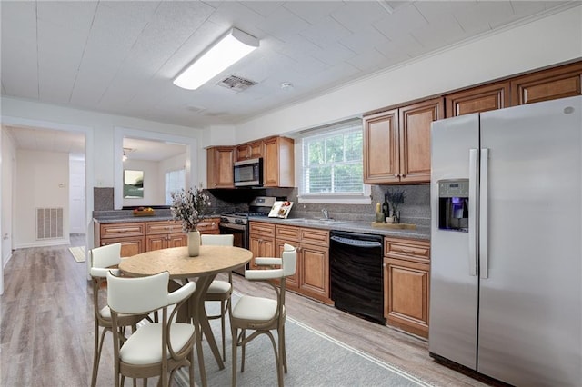 kitchen featuring stainless steel appliances, sink, backsplash, and light wood-type flooring