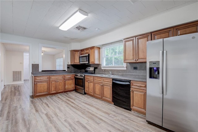 kitchen featuring stainless steel appliances, sink, backsplash, and light hardwood / wood-style flooring