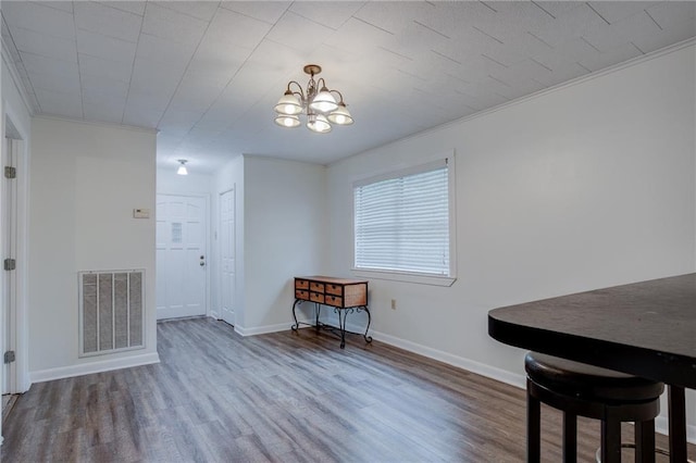 dining space with wood-type flooring, ornamental molding, and a chandelier