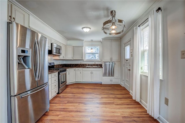 kitchen featuring appliances with stainless steel finishes, sink, white cabinets, light hardwood / wood-style floors, and crown molding