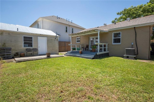 rear view of property with a deck, a lawn, and central air condition unit