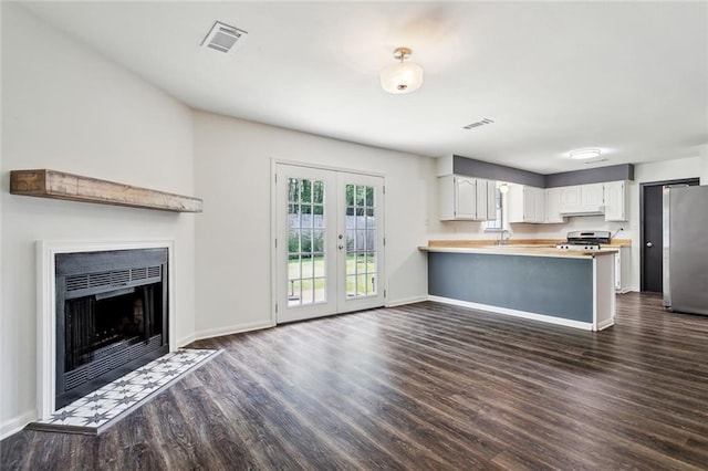 kitchen featuring dark wood-style floors, french doors, freestanding refrigerator, range, and a peninsula