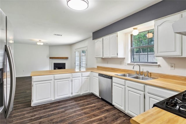 kitchen featuring dark wood-style flooring, stainless steel appliances, visible vents, a sink, and a peninsula