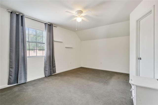 carpeted spare room featuring lofted ceiling, ceiling fan, and baseboards