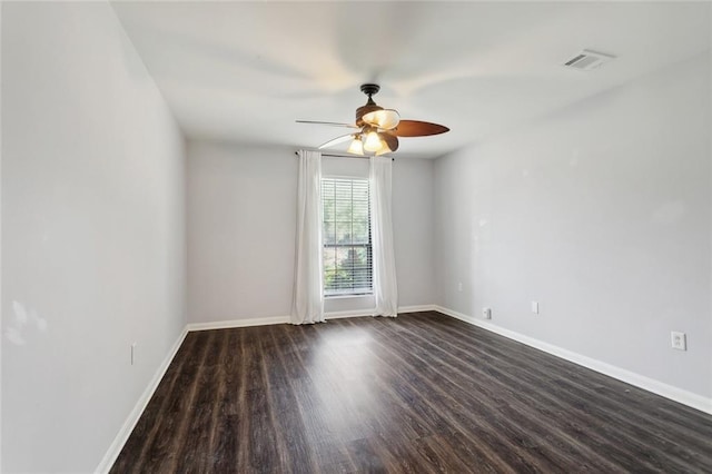 spare room featuring dark wood-style floors, ceiling fan, visible vents, and baseboards