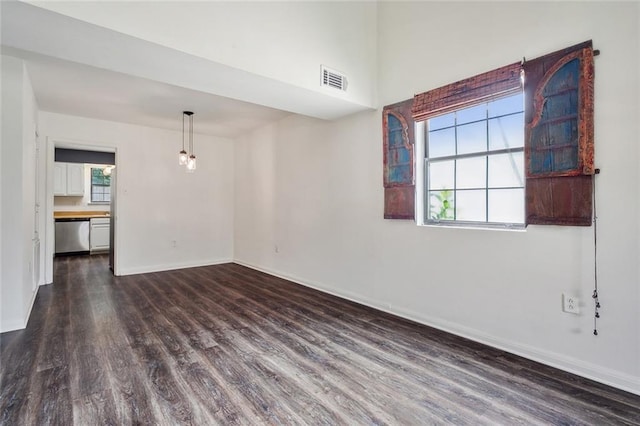 spare room with dark wood-style floors, visible vents, and baseboards