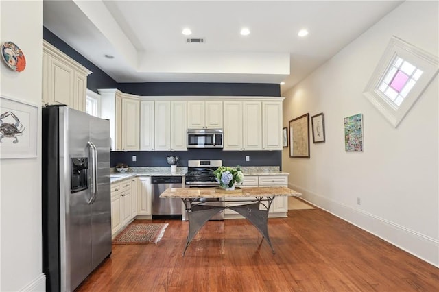 kitchen featuring hardwood / wood-style floors, cream cabinets, and stainless steel appliances