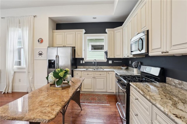 kitchen featuring light stone counters, sink, dark hardwood / wood-style flooring, and appliances with stainless steel finishes