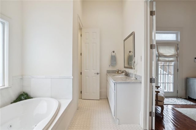 bathroom with vanity and tiled bath