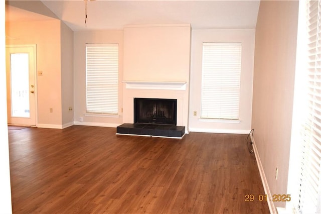 unfurnished living room featuring a tile fireplace and dark hardwood / wood-style flooring