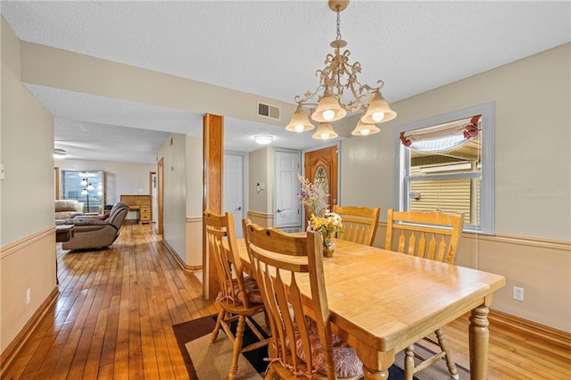 dining space with hardwood / wood-style flooring, a notable chandelier, and a textured ceiling