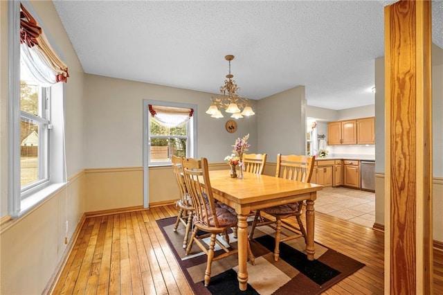 dining area featuring an inviting chandelier, light hardwood / wood-style floors, and a textured ceiling