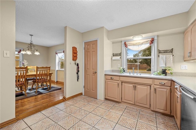 kitchen with light brown cabinets, a sink, light countertops, hanging light fixtures, and dishwasher