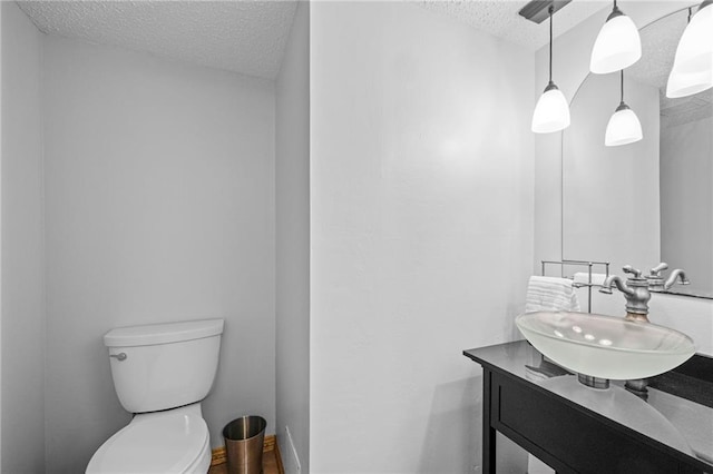 bathroom featuring baseboards, toilet, a textured ceiling, and vanity