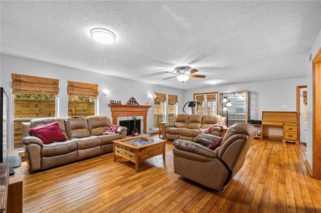 living room featuring ceiling fan, a textured ceiling, and light wood-type flooring