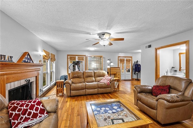 living area featuring visible vents, a fireplace, a textured ceiling, and wood finished floors