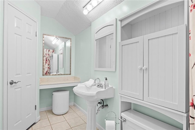 full bath with toilet, vaulted ceiling, a textured ceiling, tile patterned flooring, and baseboards