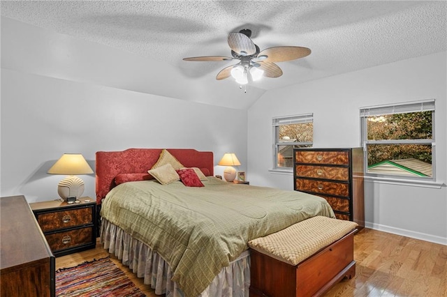 bedroom featuring light wood-type flooring, baseboards, a textured ceiling, and lofted ceiling