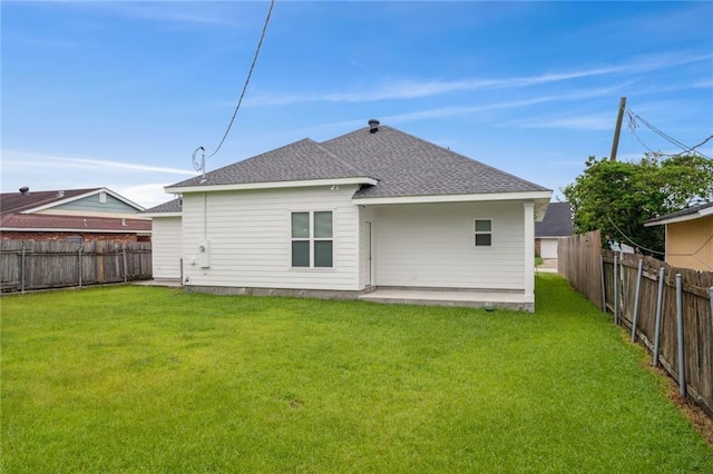 rear view of property featuring a patio, a lawn, a fenced backyard, and a shingled roof