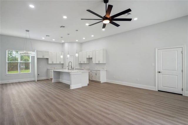 kitchen featuring ceiling fan, open floor plan, light wood-type flooring, light countertops, and white cabinetry