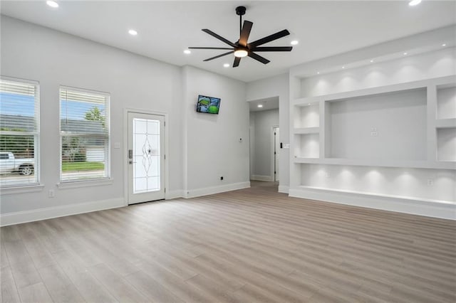 unfurnished living room featuring built in shelves, recessed lighting, light wood-type flooring, and ceiling fan