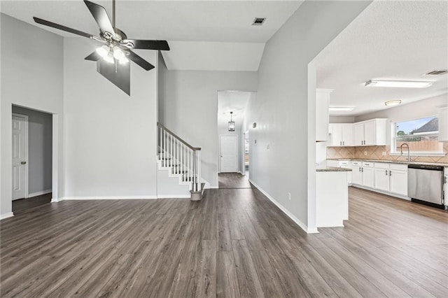 interior space with a sink, wood finished floors, visible vents, stairs, and baseboards