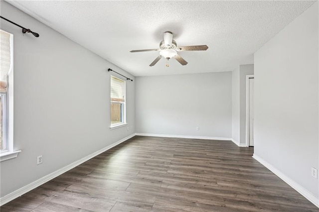 empty room featuring a textured ceiling, dark wood-type flooring, a ceiling fan, and baseboards