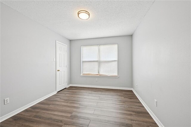 empty room featuring dark wood-type flooring and a textured ceiling