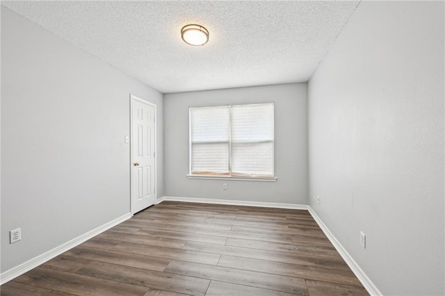 unfurnished room with dark wood-style flooring, a textured ceiling, and baseboards