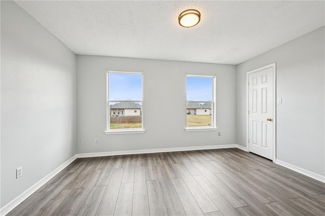 unfurnished room featuring hardwood / wood-style floors, a textured ceiling, and a wealth of natural light