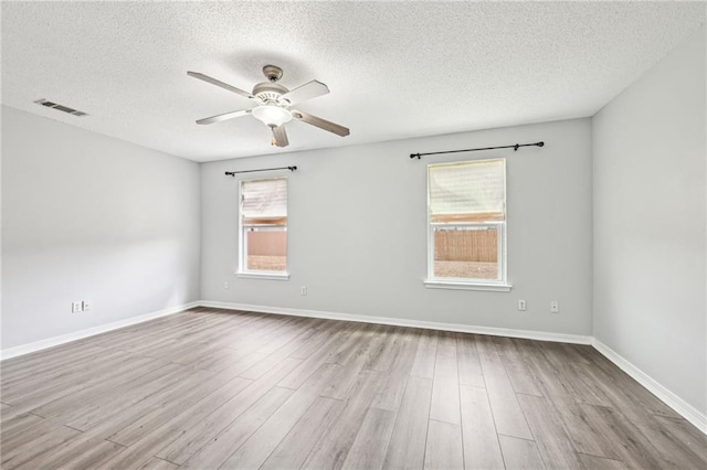 unfurnished room with a ceiling fan, baseboards, visible vents, and wood finished floors