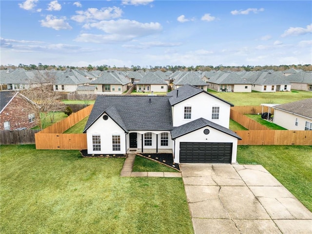 view of front facade with concrete driveway, a front yard, fence private yard, a garage, and a residential view