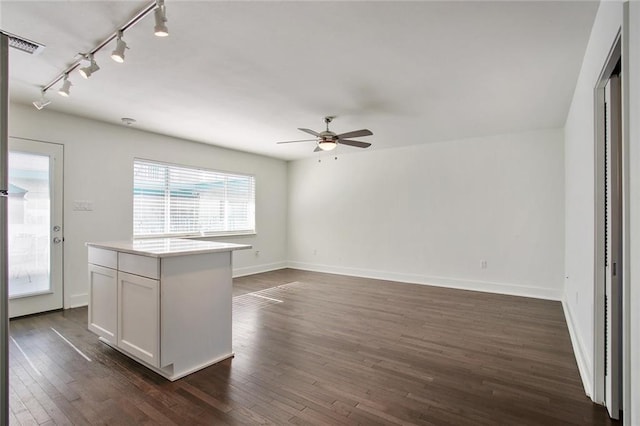 interior space with dark hardwood / wood-style floors, white cabinetry, a center island, ceiling fan, and track lighting