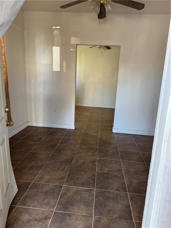 tiled empty room featuring ceiling fan