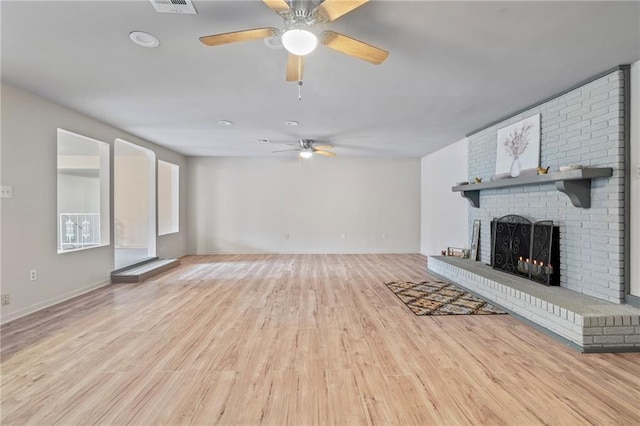 unfurnished living room featuring ceiling fan, a brick fireplace, and light wood-type flooring