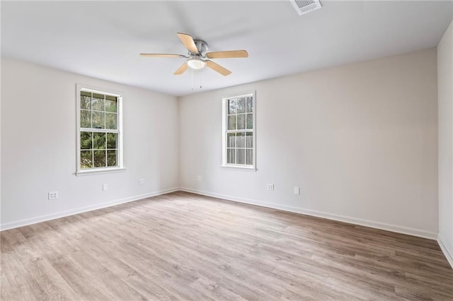 empty room with ceiling fan, hardwood / wood-style floors, and a wealth of natural light