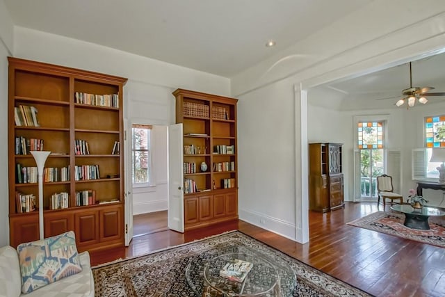 living area featuring dark wood-type flooring and ceiling fan