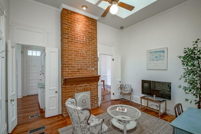 living room featuring ornamental molding, a towering ceiling, ceiling fan, and light wood-type flooring