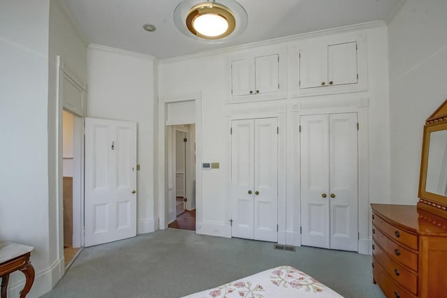 bedroom featuring crown molding, two closets, and dark colored carpet