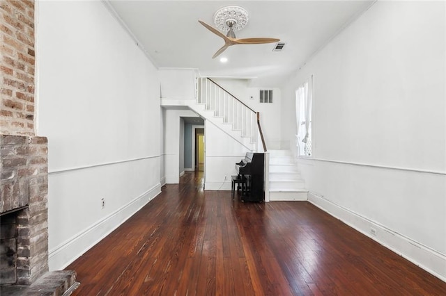 unfurnished living room featuring a brick fireplace, dark hardwood / wood-style floors, and ceiling fan