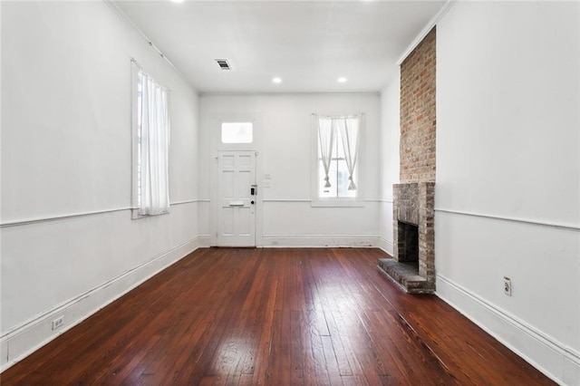 unfurnished living room with dark wood-type flooring and a brick fireplace