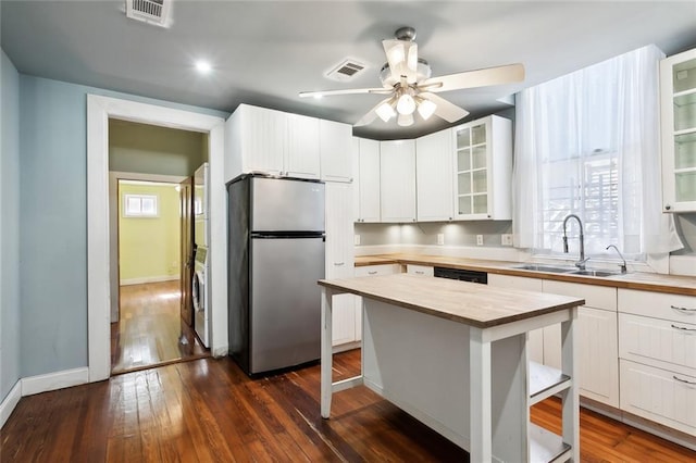 kitchen with sink, white cabinets, stainless steel fridge, dark hardwood / wood-style flooring, and a center island