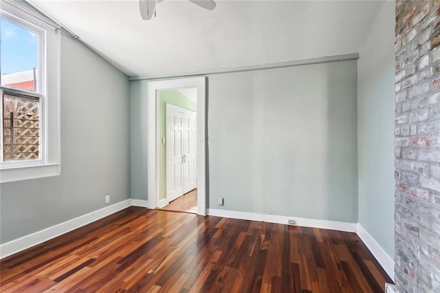 empty room featuring hardwood / wood-style floors, ceiling fan, and brick wall