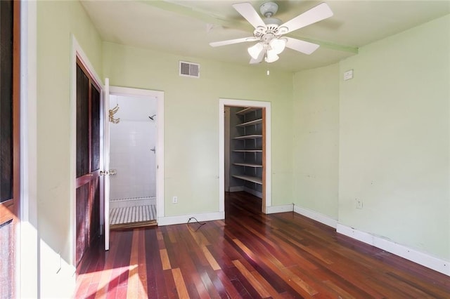 unfurnished bedroom with ceiling fan, a walk in closet, dark hardwood / wood-style flooring, and a closet