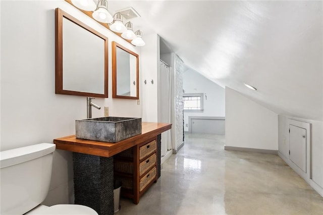 bathroom with vaulted ceiling, toilet, sink, and concrete floors